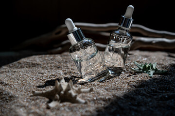 Two glass bottles of face serum on a sea background.
