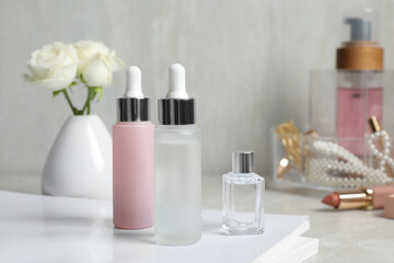 Fototapeta na wymiar Bottles of cosmetic products on light grey table