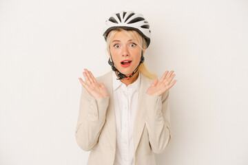 Young business Russian woman holding bike helmet isolated on white background surprised and shocked.