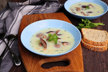Creamy soup with boletus mushroom and herbs on wooden table