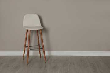 Stylish bar stool near light grey wall indoors. Space for text
