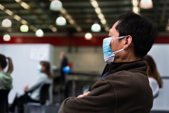 People Wearing Double Face Mask And Waiting For The Corona Virus Vaccination. People Sitting 2 Meters Apart, Auckland.