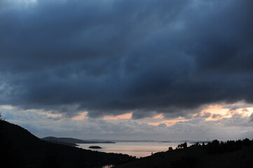 Dramatic panorama and landscape from a hill above sea coast with clouds during sunset at dusk in the evening