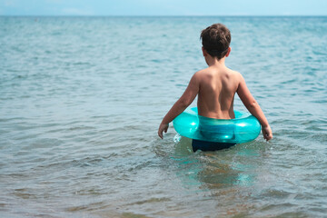 Boy with inflatable ring standing in the sea.