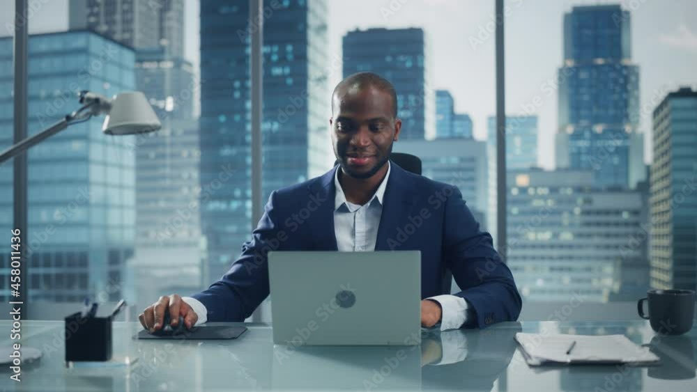 Poster portrait of thoughtful black businessman working on laptop computer in his big city office. charisma