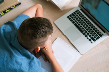 Teen boy lying on the floor in front of a laptop