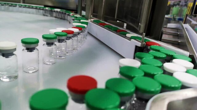 small glass bottles for medicine move on a white conveyor