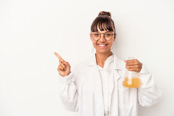 Young mixed race scientist woman holding a test tube isolated on white background  smiling and pointing aside, showing something at blank space.