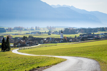 Road to Austrian mountain village with foggy valley background in autumn, Wildermieming, Tirol, Austria