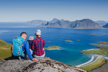 Father, mother and son on a mountain top looking at Norway beautiful view. Lofotens