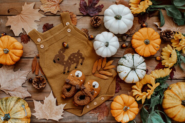 Baby autumn wear clothes with pumpkins and leaves on brown background. Top view. Cute warm kid...