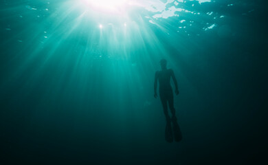Underwater photo of freediver ascending to sea surface