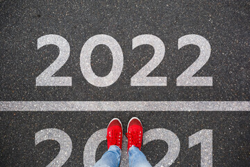 Red sneakers on the asphalt road with passing 2021 to 2022. Concept for success in the future goal...