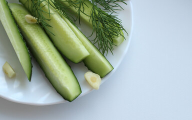 low-salt slices of cucumbers with dill and garlic on a saucer on a light background