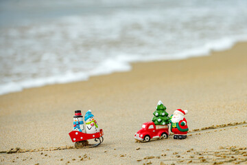 Christmas background. Toy Santa and snowman on summer beach, concept for travel in hot countries.