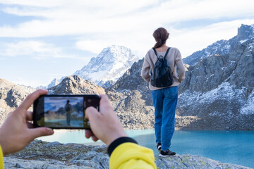 couple hiking on mountain on autumn day. man taking photo on phone of his girlfriend