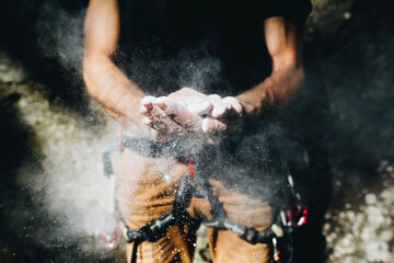 Fototapeta na wymiar Climber man coating his hands in powder chalk magnesium. Ready for climbing