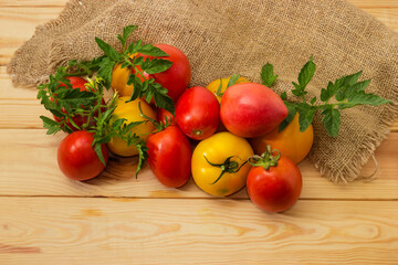 Colorful tomatoes with twigs and leaves on the rustic table