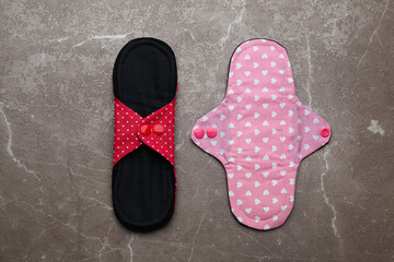 Reusable cloth menstrual pads on brown table, flat lay