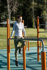 athletic ginger woman working out outdoor on urban sports ground in sunny autumn day