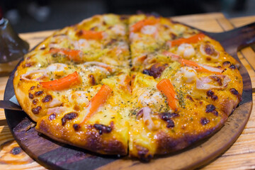 Seafood (delicious crab sticks, squid, shrimp) with cheese pizza is served on top with oregano powder and chopped as pieces, ready to eat. It’s a America fast food.