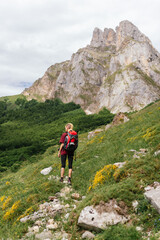 Fototapeta na wymiar Young female traveler, with a backpack on her back, ascending a mountain during an excursion through the Picos de Europa National Park.