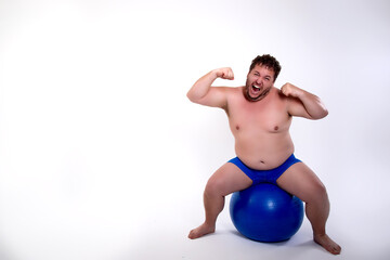 Obraz premium Funny fat man training with a fitness ball. Adult guy on a white background. Copy space. Active sports with a diet. 