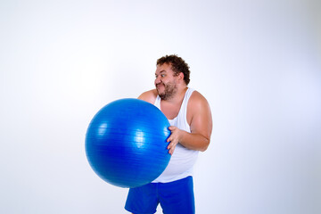 Funny fat man training with a fitness ball. Adult guy on a white background. Copy space. Active sports with a diet.	
