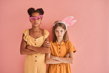 Little girls standing arms crossed and looking seriously while posing to the camera