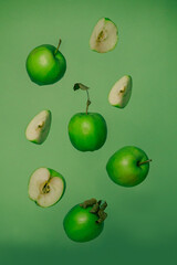 Flying fresh green apple with seeds on green background. Apple or fruits in the air
