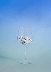 dices in a wine glass on a sky blue  background.minimal still life abstract design concept