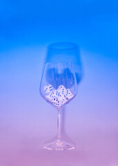 dices in a wine glass on a sky blue and pink neon background.minimal still life abstract design concept