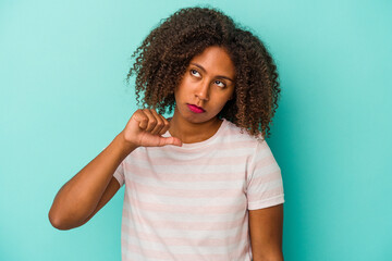 Young african american woman with curly hair isolated on blue background showing a dislike gesture, thumbs down. Disagreement concept.
