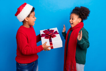 Photo of impressed funky dark skin children wear pullover headwear scarf giving present isolated blue color background
