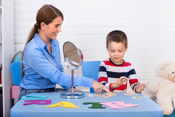 Toddler boy in child occupational therapy session doing sensory playful exercises with her...