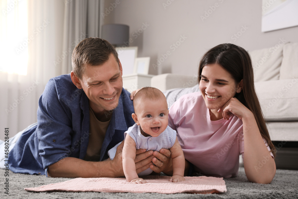 Poster happy family with their cute baby on floor at home