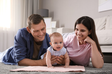 Happy family with their cute baby on floor at home