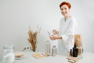 Portrait of a short haired woman pouring water in a metal thermos from a jug