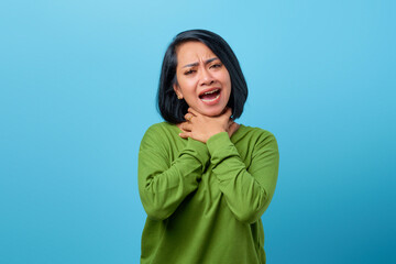 Attractive Asian woman wearing casual clothes strangle neck with both hand on blue background