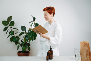 Smiling short-haired woman looking at the notebook with a carton cover