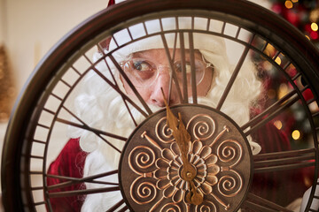 Five minutes to New year or Christmas midnight.  Happy Santa Claus shows on the clock
