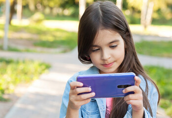 Fototapeta premium Happy child girl with phone outdoors. Gagets consept