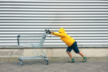Girl in yellow jacket pushes shopping cart and looks heavy © Amparo Garcia