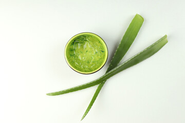 Aloe leaves and bowl with gel on white background