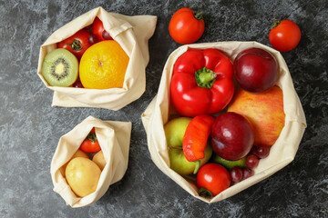 Bags with vegetables and fruits on black smokey table