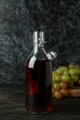 Bottle of vinegar and grape on rustic wooden table