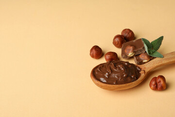 Spoon with chocolate paste, nuts, chocolate and mint on beige background