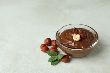 Bowl with chocolate paste, nuts and mint on white textured background