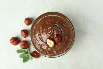 Bowl with chocolate paste, nuts and mint on white textured background