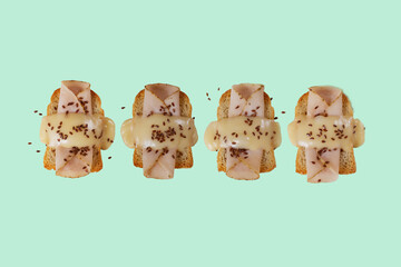 Toasted bread with ham, yellow cheese and flax seeds with a green, purple and blue background.